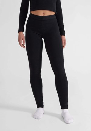 Leggings neri realizzati in tessuto elasticizzato, caratterizzati da una vita alta e una texture liscia. Abbinati a calze bianche.
