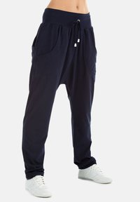 Navy blue harem pants made from soft fabric, featuring a wide elastic waistband, large front pockets, and a relaxed fit.