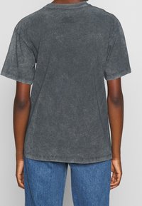 Mörkgrå, t-shirt med kort ärm och en något urblekt textur, rund halsringning och avslappnad passform. Synlig sömnad och inga tryck på baksidan.