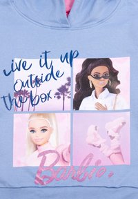 Design a quattro pannelli con palme, due bambole Barbie vestite in modo alla moda e stivali rosa; il testo recita "Vivi al massimo al di fuori dagli schemi. Barbie."