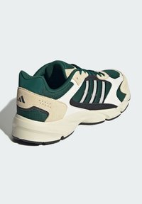 Baskets sportives en mesh vert foncé et en suède, avec des panneaux blancs et des accents noirs. Semelle Cloudfoam rembourrée pour le confort.