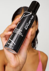 Zwarte cilindrische spuitbus met het label "Kaze Wave Curl Mousse," voorzien van een wit logo, duidelijke meetafbeeldingen en een glanzende afwerking.