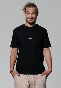 Schwarzes Baumwoll-T-Shirt mit einem weißen Textgrafik "Nope." auf der Vorderseite. Kurze Ärmel, entspannter Schnitt, glatte Textur.