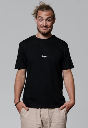 Zwarte katoenen T-shirt met een witte tekstafbeelding "Nope." op de voorkant. Korte mouwen, relaxte pasvorm, soepele textuur.