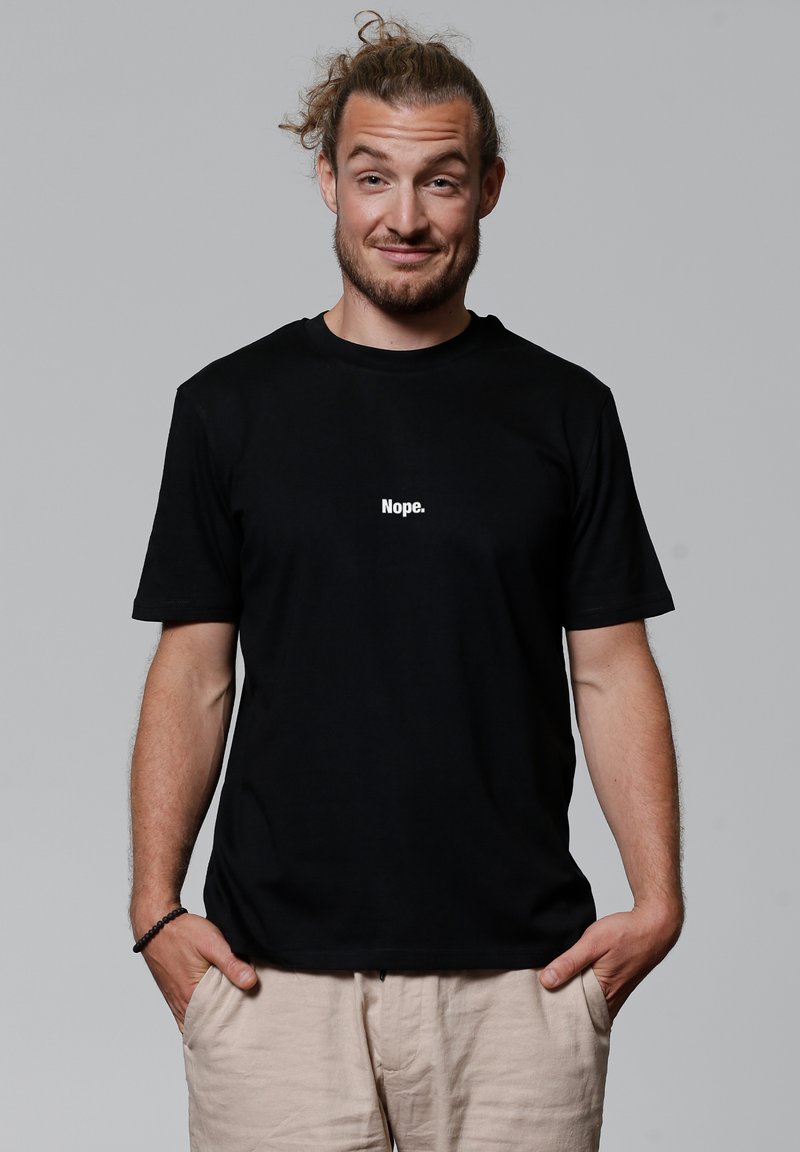 Schwarzes Baumwoll-T-Shirt mit einem weißen Textgrafik "Nope." auf der Vorderseite. Kurze Ärmel, entspannter Schnitt, glatte Textur.