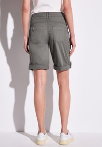 Shorts en coton gris avec des revers roulés, deux poches arrière et une texture lisse. Présente des coutures minimales et un design durable.