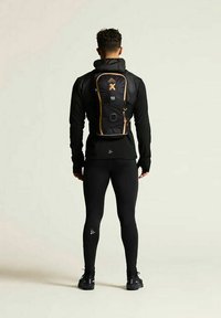 Schwarzer Sportrucksack mit orangen Akzenten, angepasst an eine Figur in einem schwarzen Langarmoberteil und Leggings; glatte Textur und aerodynamisches Design.