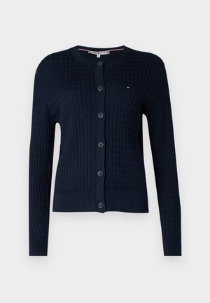 Cardigan tricotat de culoare albastru marin, cu design în cablu, având un guler rotund, mâneci lungi și nasturi pe față. Detaliul subtil cu logo este prezent.