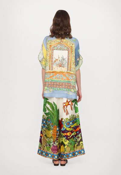 Multifarvet outfit med en mønstret, kortærmet skjorte med blå bund og brede bukser med livlige botaniske motiver.