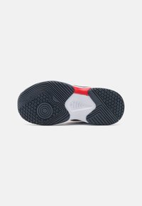 Suola della scarpa in materiale gommoso; presenta motivi testurizzati, una sezione centrale bianca e un design nero e rosso.