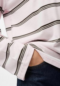 Kerged varrukatega triibuline särk heleses roosas värvitoonis, millel on tumedatest pruunidest horisontaalsed triibud. Särk on valmistatud pehmest kangast, millel on tasku detail ja lõdvestatud sobivus.