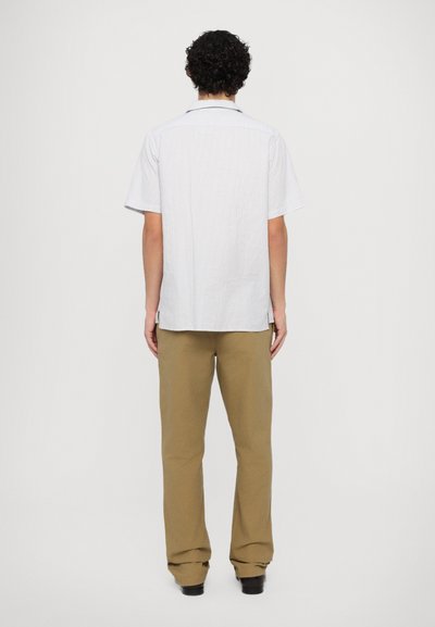 Short-sleeve, light-colored striped shirt with a pointed collar, paired with tan, wide-leg trousers and black shoes.