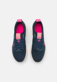 Marinefargede mesh-sneakers med rosa og grønne detaljer, en teksturert overdel, og en QR-kode på tungen. Har en hvit såle og matchende snøringer.