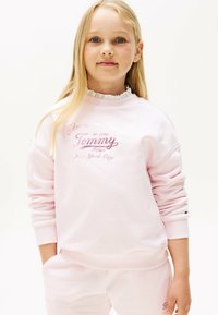 Felpa rosa con collo arricciato, caratterizzata da una stampa a logo in testo lucido. Realizzata in tessuto morbido, con polsini e orlo a coste.