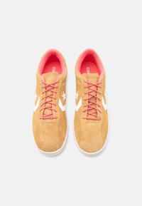 Ζευγάρι ταμπά σουέντ αθλητικά παπούτσια με λευκά λογότυπα αστεριού και σχήματος βέλους, ροζ κορδόνια και ροζ εσωτερική επένδυση σε λευκό φόντο.