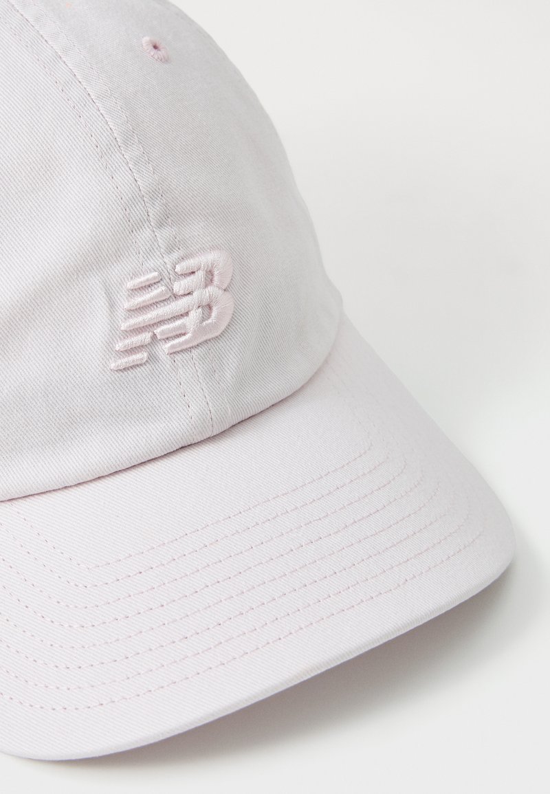 Lichtroze baseballcap van katoen, met een gestikte New Balance-logo op de voorkant, voorzien van een gebogen rand en zichtbare stiksels.