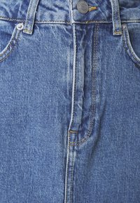Jeans in denim di un blu medio con cuciture gialle, caratterizzati da una chiusura con bottone e cerniera e tasche frontali. Tessuto strutturato.