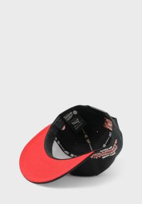 Mustapipo, jossa on punainen lippu, sisältä brändäysmerkinnät ja graafinen printti. Se on rakenteeltaan muotoiltu ja pinnaltaan sileä.