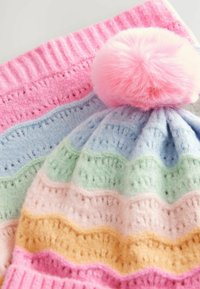 Dziane czapka z różowym pomponem, z falistymi paskami w pastelowych kolorach: niebieskim, zielonym, różowym, żółtym i kremowym, o miękkiej, teksturowanej fakturze.