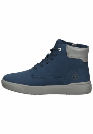 Zapatillas altas de color azul marino hechas de cuero suave, con un cuello acolchado gris, suela texturizada gris y logotipo en el lateral.