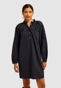Abito in cotone blu navy con scollatura plissettata, chiusura a bottoni e dettagli ricamati sulle maniche. Maniche lunghe a sbuffo e vestibilità comoda.