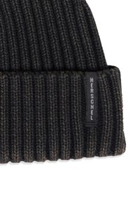 Pletená čiapka v tmavosivej a čiernej farbe s rebrovanou textúrou. Na ohybe sa nachádza malá čierna nášivka s logom "Herschel".