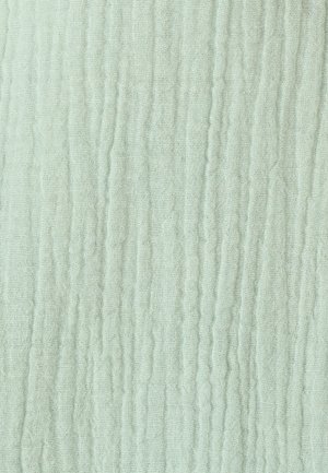 Tissu en mousseline vert clair froissé avec une texture douce et gazeuse et des lignes de plis verticales.