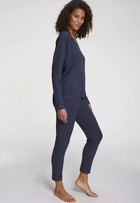 Navy blue ribbed loungewear set featuring a long-sleeve top with a V-neck and gently tapered pants, made of soft, textured material.