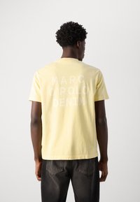 Light yellow cotton t-shirt with a round neck and short sleeves. Features a large white graphic text on the back: "MARC O'POLO DENIM."