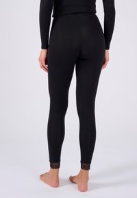 Leggings neri con una texture liscia, vita alta e bordo in pizzo alla caviglia. Il design è aderente e allunga la forma della gamba.