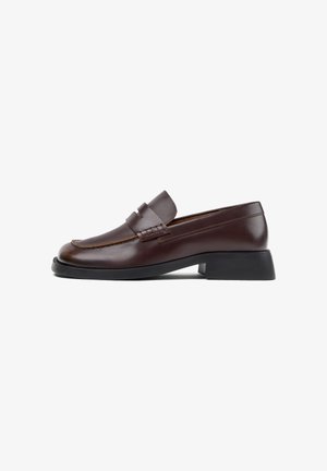 Mocassino in pelle marrone scuro con tacco basso a blocco nero e dettaglio di cinturino decorativo sulla tomaia.