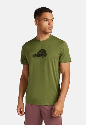 Oliven grøn t-shirt lavet af blødt stof, med en sort grafik af en campingvogn på brystet. Korte ærmer og rund halsudskæring.