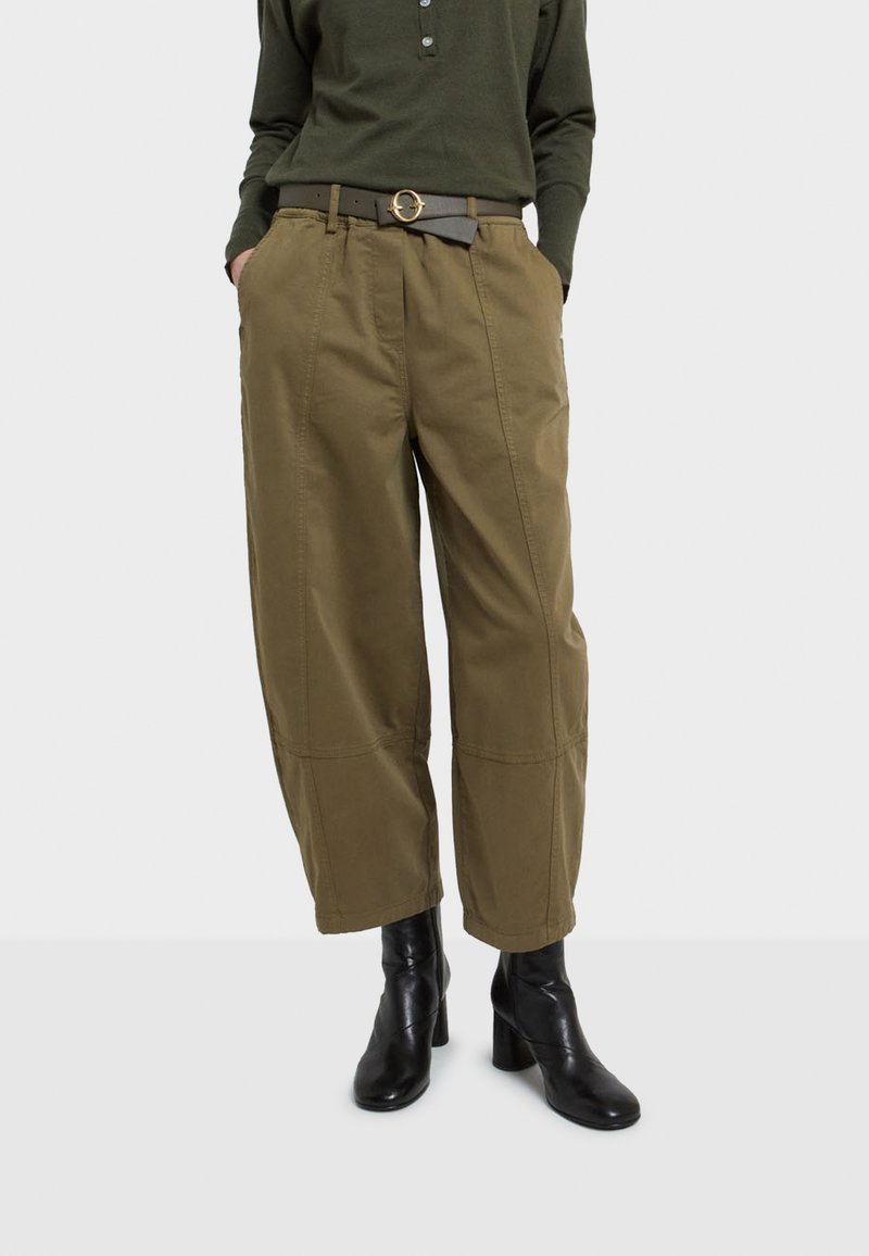 Olivovo zelené nohavice s širokými nohavicami, prednými skladmi, bočnými vreckami a prešitím na leme, v kombinácii s čiernym opaskom s okrúhlou zlatou prackou.