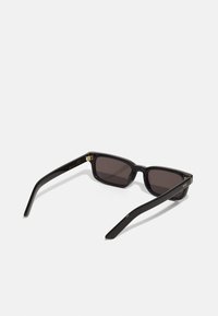 Black rectangular sunglasses with dark lenses, shiny plastic frame, gold accents on the hinges, and tapered arms.