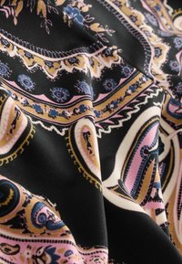 Zwart materiaal met complexe paisleypatronen in roze, blauw en gouden tinten, met een gladde textuur en elegante draping.
