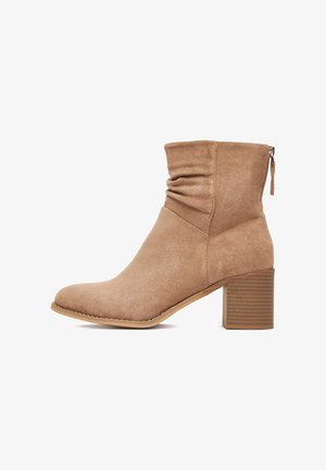 Rudos spalvos zomšos kulkšnies batai su sukritusia viršutine dalimi, šoniniu užtrauktuku ir pakrautu bloko padu. Apvalus nosis ir lygi faktūra.