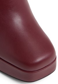 Burgundy leather ankle boot with a smooth texture, rounded toe, and a solid block heel. Features a slight sheen and clean lines.