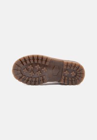 Semelle de botte en caoutchouc brun avec des crampons profonds, présentant des motifs rectangulaires et en croix, conçue pour une forte adhérence et une utilisation en extérieur.