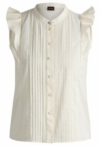 Ärmlös vit blus med knapp-up med vertikala veck och volangdetaljer på axlarna. Slät textur med delikata detaljer.