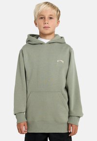 Felpa con cappuccio verde oliva, realizzata in tessuto morbido. Presenta una tasca frontale, polsini e orlo a coste, e un piccolo logo.