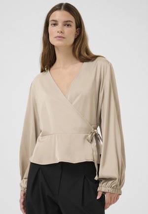 Beige wrap blouse in smooth fabric, featuring long sleeves with gathered cuffs and an adjustable tie at the waist.