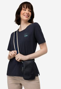 Marineblauwe katoenen T-shirt met korte mouwen, afgewerkt met een klein grafisch ontwerp. Gecombineerd met een kleine, gestructureerde marineblauwe schoudertas.