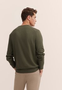 Dark olive green sweatshirt in soft fabric with ribbed collar and cuffs, featuring a relaxed fit and subtle stitching details.