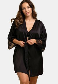Robe en satin noir avec des accents en dentelle sur les manches, dotée d'une fermeture à nouer à la taille et d'une longueur mi-thigh pour une coupe fluide.