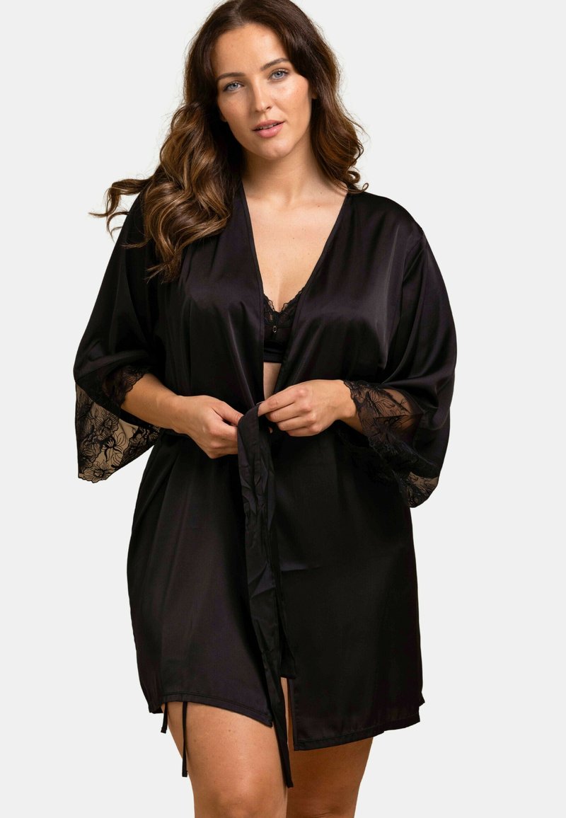 Robe en satin noir avec des accents en dentelle sur les manches, dotée d'une fermeture à nouer à la taille et d'une longueur mi-thigh pour une coupe fluide.