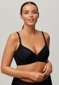 Sostén negro con aros, confeccionado en tela suave, con tirantes ajustables y un botón decorativo central. Diseñado para una apariencia sin costuras.