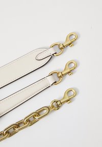 Leather straps in white with gold-tone hardware. Features smooth texture, rounded edges, and sturdy clasp connectors. Chain-link detail included.