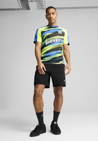 Puma sports trøje med sorte, grønne og blå bølgemønstre samt teksten "Olympique de Marseille". Parret med sorte shorts og sokker.