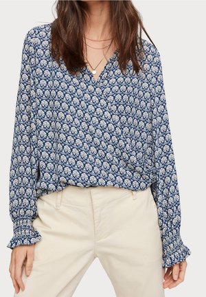 Bluse in Marineblau und Weiß mit Muster, V-Ausschnitt, langen Ärmeln und elastischen Rüschensäumen. Aus leichtem Stoff gefertigt und mit floralem Design.