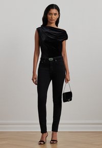 Svart fløyels av-og-på skuldre topp med drapert design, parret med svarte skinny jeans, svarte stroppede hæler og en liten svart håndveske.